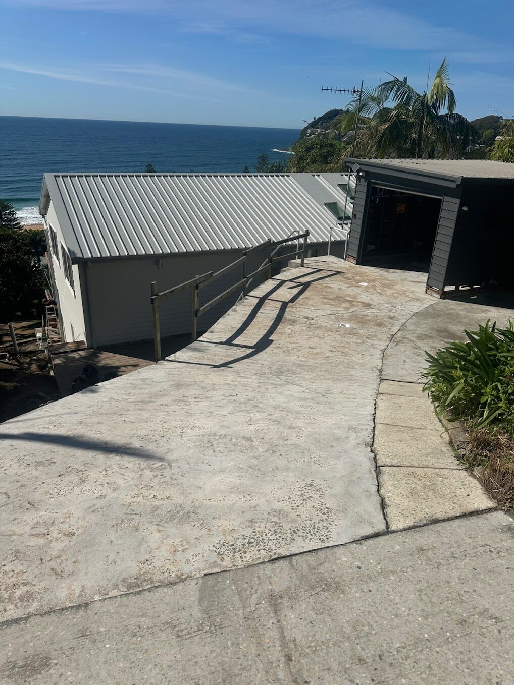Whale Beach sloping driveway before resurfacing — failing concrete and old epoxy paint